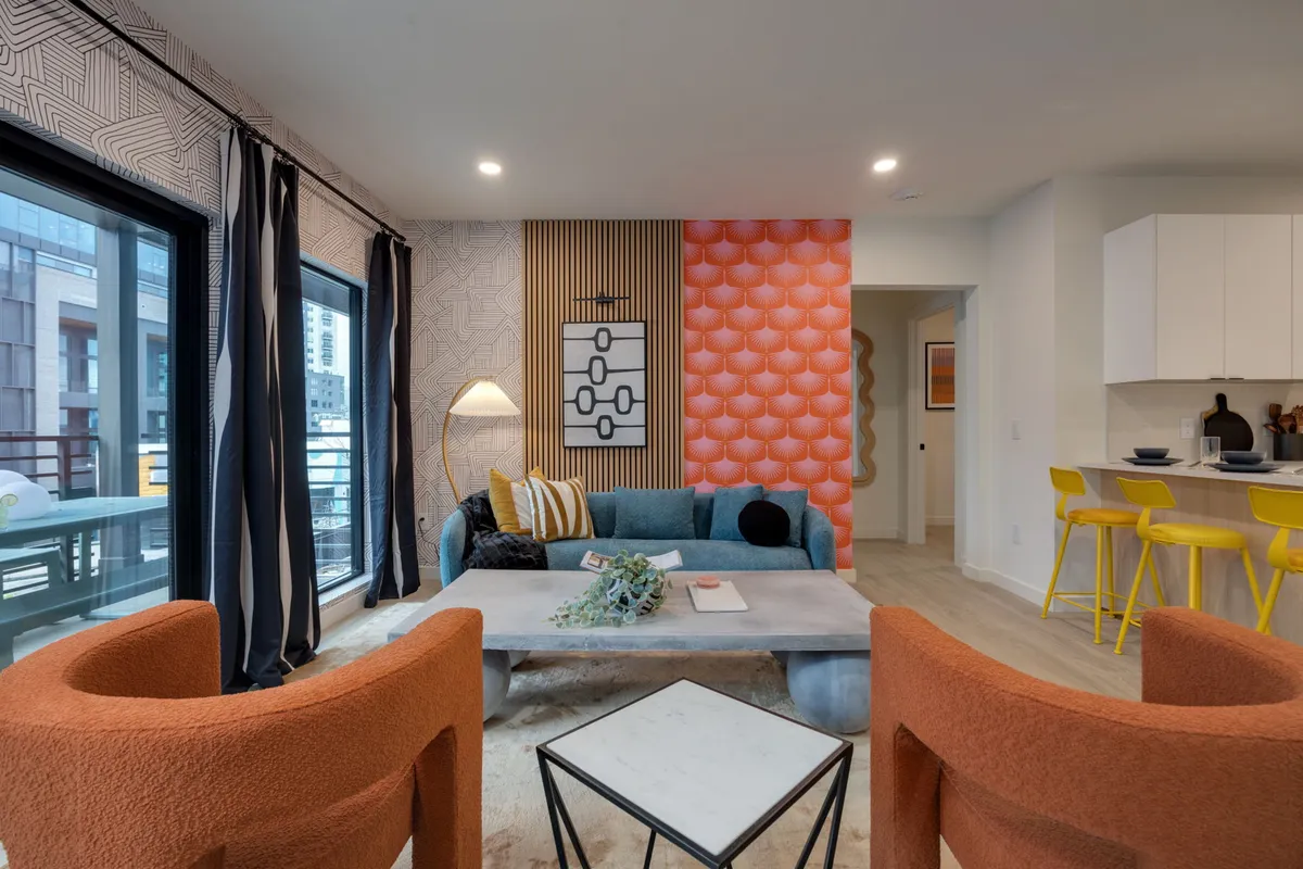 A stylish entry/foyer area with a colorful accent wall, modern seating arrangement, decorative lighting, and a chic coffee table. The design is contemporary and welcoming, signaling an effortless and secure arrival.
