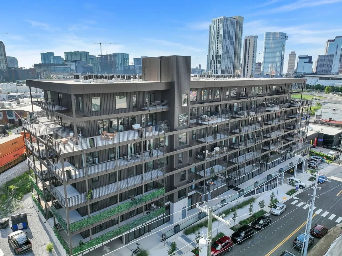 A breathtaking rooftop lounge with modern architecture, balconies adorned with greenery, and panoramic views of the city skyline. The space encourages sunset gatherings and social relaxation in an urban oasis setting.